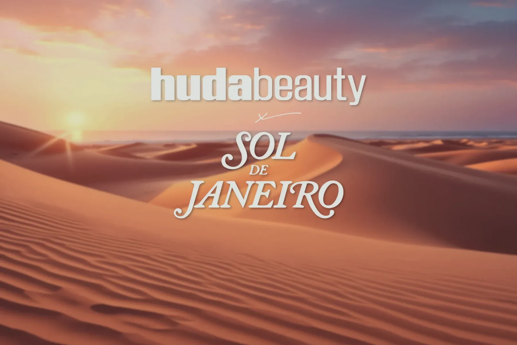 The Huda Beauty × Sol de Janeiro lockup over desert dunes at sunset